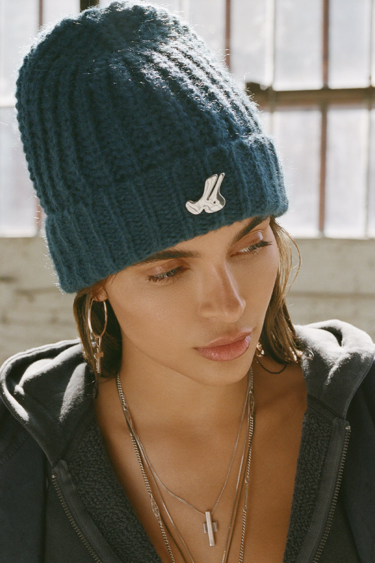 Front view of model posing in the soft and warm spruce Knit Beanie that has removable custom JOAH BROWN pin.