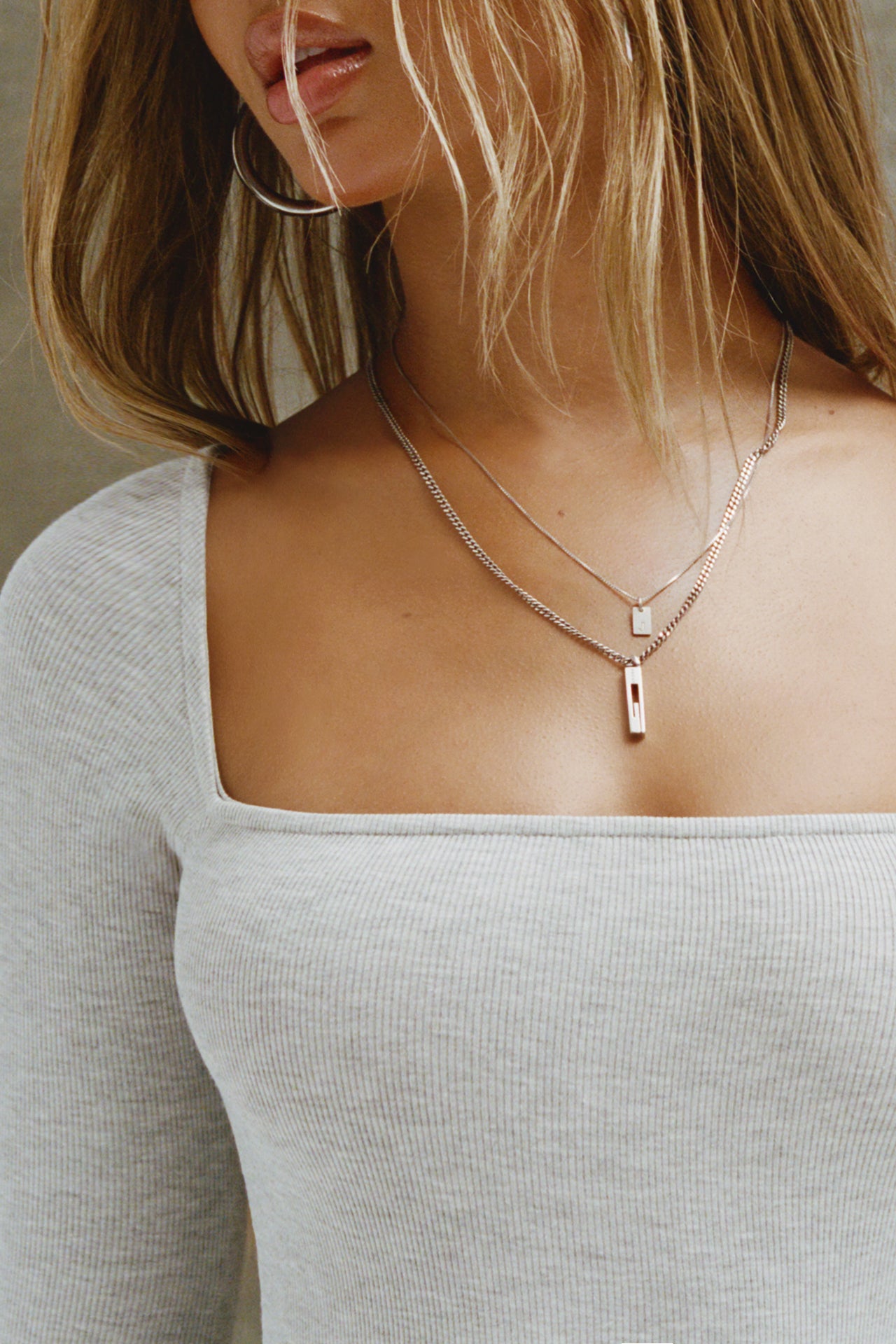 Close up detail front view of model posing in the fitted and stretchy pearl grey rib Square Neck Long Sleeve top with a wide square neckline