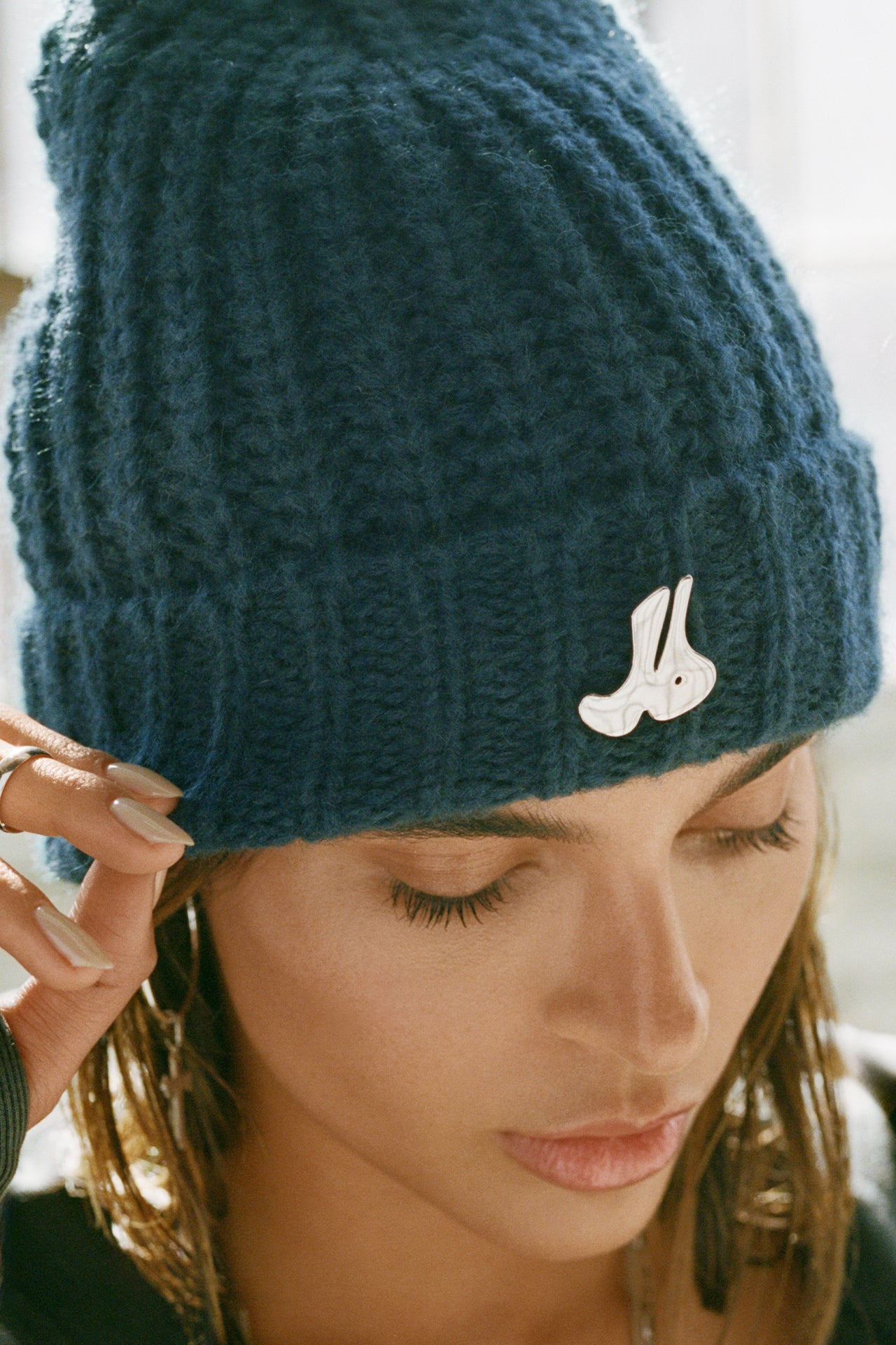 Close up detail front view of model posing in the soft and warm spruce Knit Beanie that has removable custom JOAH BROWN pin.