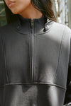 Close up detail front view of model posing in the oversized comfortable charcoal luxe french terry Retro Half Zip pullover sweatshirt with ribbed accents on the chest and sleeves, a hidden kangaroo pocket and a half zip collar