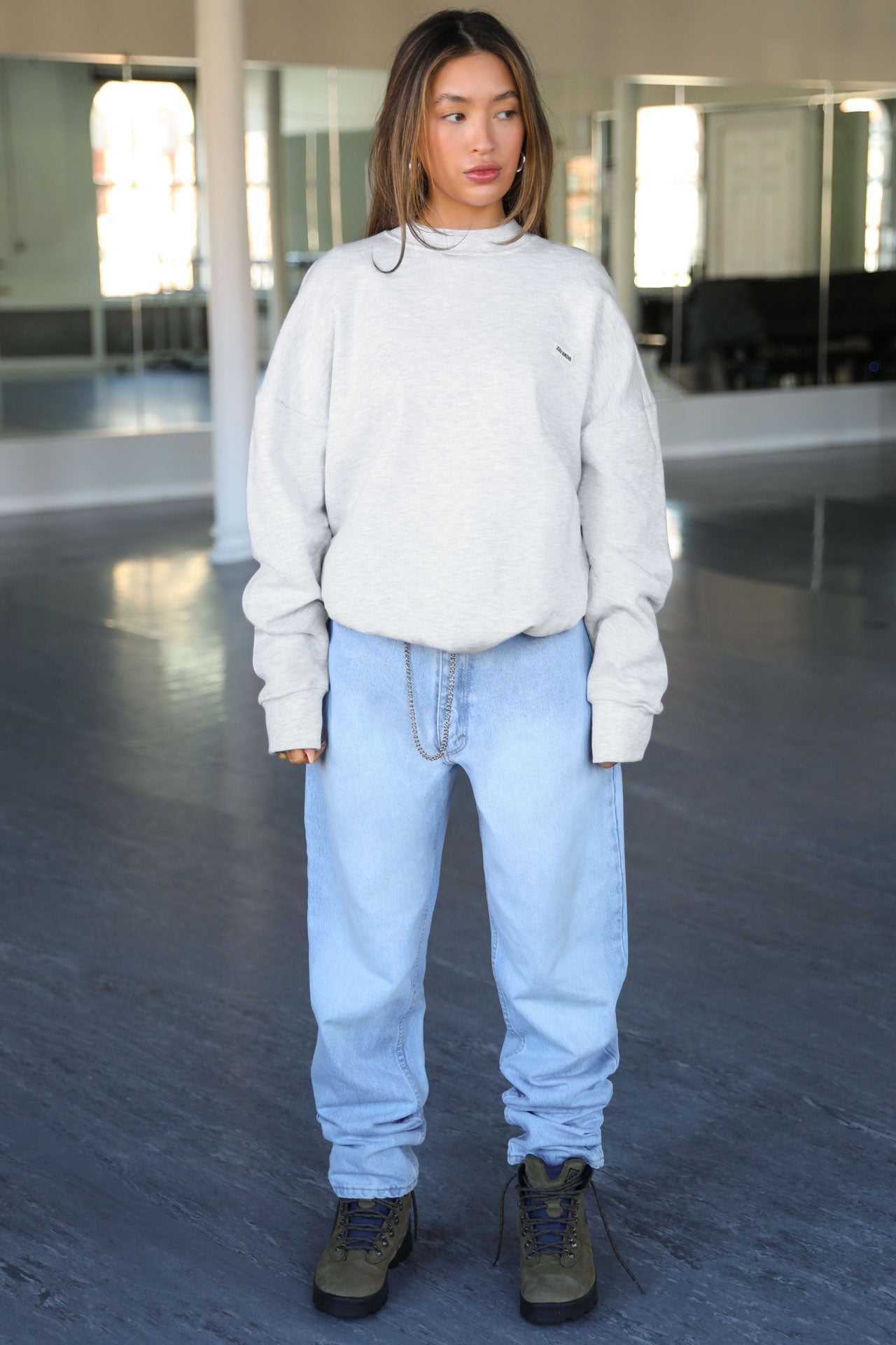 Full body front view of model posing in the soft oversized pearl grey french terry Classic Crew Pullover sweatshirt with a crew neckline and joah brown logo patch sewn on the upper left chest