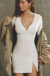 Front view of model posing in the soft and fitted natural luxe knit Asymmetrical Button Mini Dress with long sleeves,  a v-neckline and asymmetrical button-front details. 