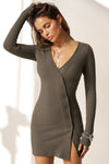 Front view of model posing in the soft and fitted army luxe knit Asymmetrical Button Mini Dress with long sleeves,  a v-neckline and asymmetrical button-front details. 