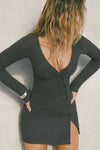 Front view of model posing in the soft and fitted ink luxe knit Asymmetrical Button Mini Dress with long sleeves,  a v-neckline and asymmetrical button-front details. 