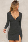 Front view of model posing in the soft and fitted ink luxe knit Asymmetrical Button Mini Dress with long sleeves,  a v-neckline and asymmetrical button-front details. 