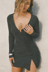 Front view of model posing in the soft and fitted ink luxe knit Asymmetrical Button Mini Dress with long sleeves,  a v-neckline and asymmetrical button-front details. 