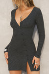 Front view of model posing in the soft and fitted ink luxe knit Asymmetrical Button Mini Dress with long sleeves,  a v-neckline and asymmetrical button-front details. 