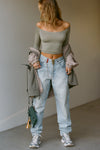 Full body front view of model posing in the fitted, slightly cropped sage modal Bare Shoulder Long Sleeve top with a straight, off-the-shoulder neckline