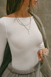 Detail front view of model posing in the fitted, light weight white modal Boatneck Long Sleeve with a boat neckline