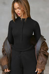 Front view of model posing in the fitted and stretchy black rib Button Down Henley long sleeve top with a high crew neckline and front buttons that reach about halfway down the shirt