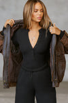 Front view of model posing in the fitted and stretchy black rib Button Down Henley long sleeve top with a high crew neckline and front buttons that reach about halfway down the shirt