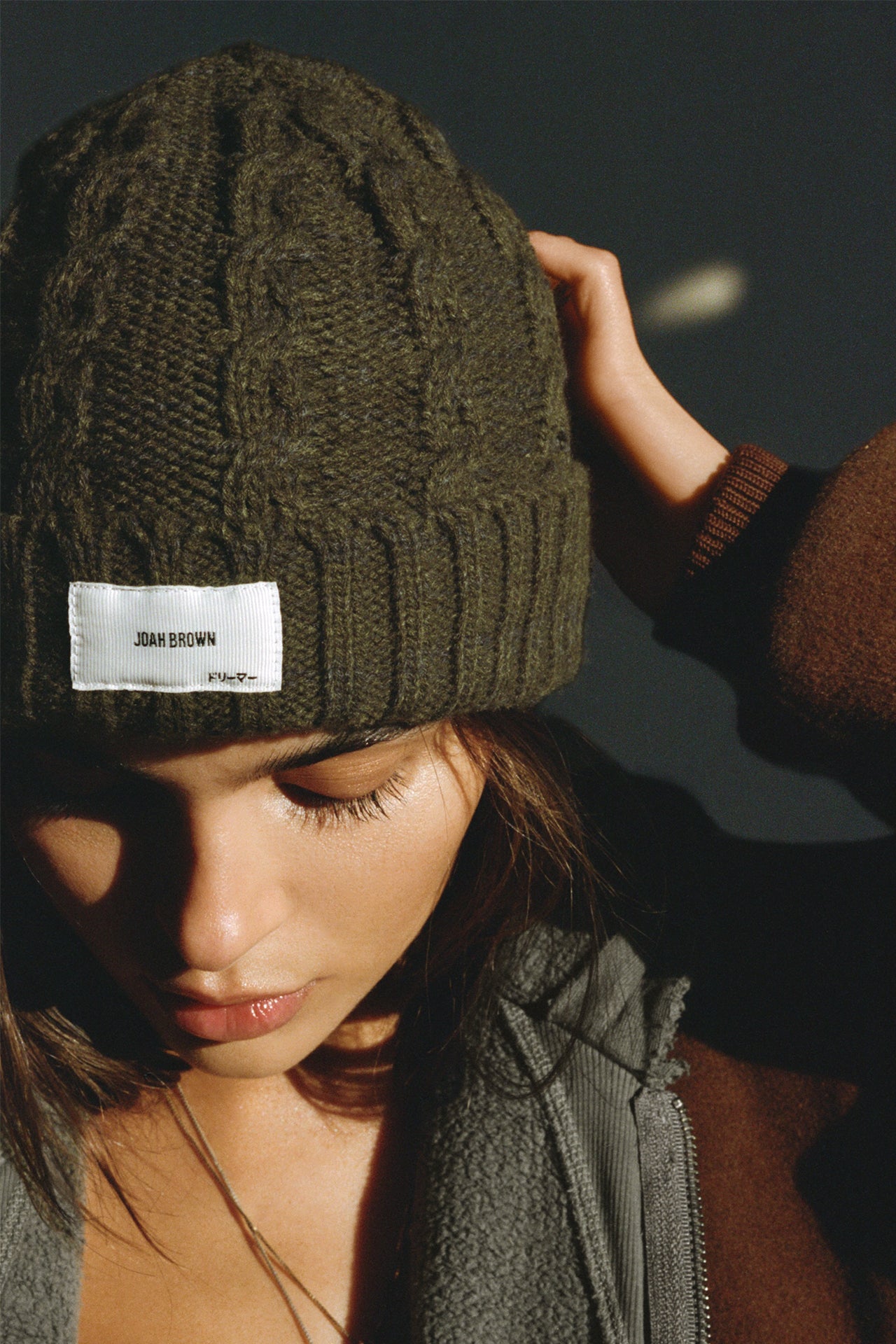 Front view of model posing in the soft and warm moss Cable Knit Beanie that has a custom JOAH BROWN "Dreamer" logo patch on the front