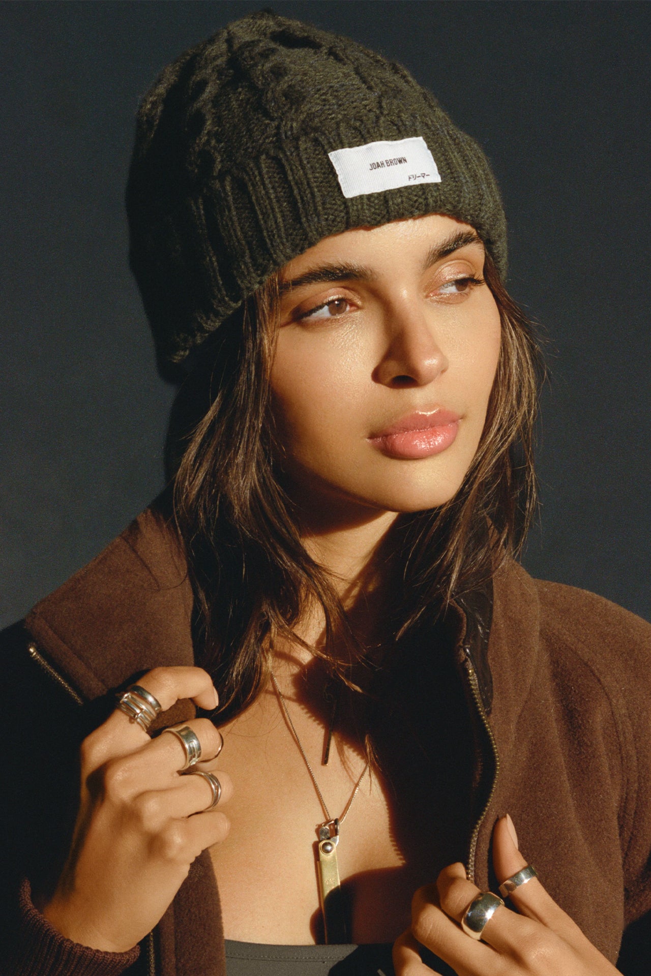 Front view of model posing in the soft and warm moss Cable Knit Beanie that has a custom JOAH BROWN "Dreamer" logo patch on the front