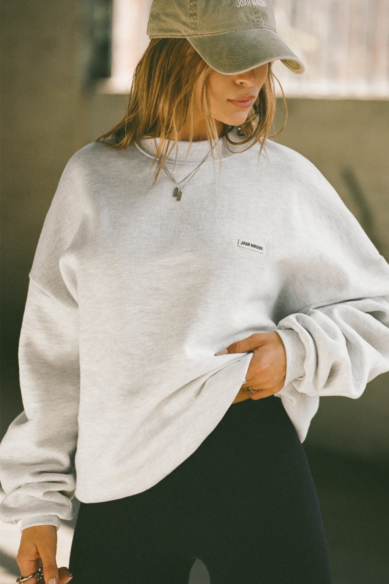 Front view of model posing in the soft oversized pearl grey french terry Classic Crew Pullover sweatshirt with a crew neckline and joah brown logo patch sewn on the upper left chest