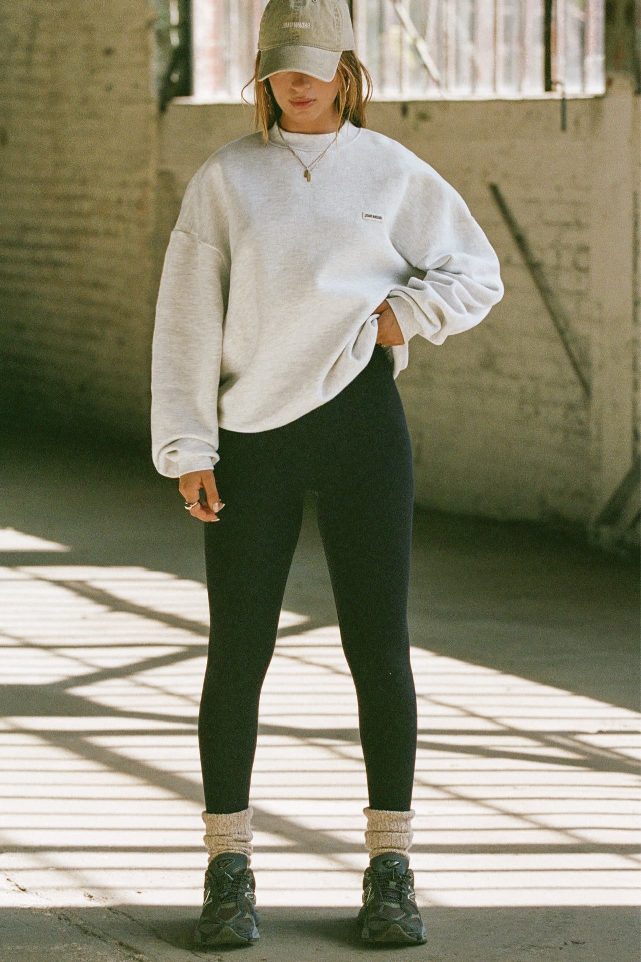 Full body front view of model posing in the soft oversized pearl grey french terry Classic Crew Pullover sweatshirt with a crew neckline and joah brown logo patch sewn on the upper left chest