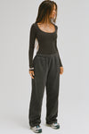 Full body front view of model posing in the fitted and stretchy vintage black rib Classic Scoop Long Sleeve with a scoop neckline