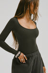 Side view of model posing in the fitted and stretchy vintage black rib Classic Scoop Long Sleeve with a scoop neckline