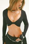 Front view of model posing in the ultra-cropped, sueded onyx Contour Clasp Long Sleeve top with a deep v neckline, thumb holes and a center clasp closure which can be worn front or back