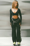 Full body front view of model posing in the ultra-cropped, sueded onyx Contour Clasp Long Sleeve top with a deep v neckline, thumb holes and a center clasp closure which can be worn front or back