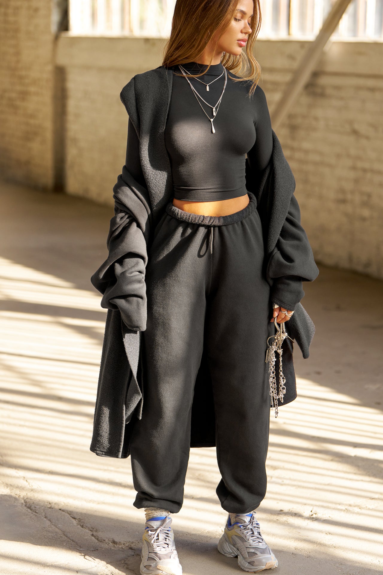 Front view of model posing in the fitted soft black modal Cropped Mock Neck Long Sleeve top with a raw cut hem