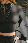 Close up front view of model posing in the fitted soft black modal Cropped Mock Neck Long Sleeve top with a raw cut hem