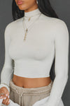 Close up front view of model posing in the fitted soft chalk modal Cropped Mock Neck Long Sleeve top with a raw cut hem