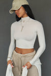 Front view of model posing in the fitted soft chalk modal Cropped Mock Neck Long Sleeve top with a raw cut hem