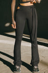 Front view of model from the waist down posing in the fitted, bootcut style sueded onyx Cutout Mini Flare Legging with a side keyhole cutout and strappy, self-adjusting ties at the waist