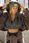 Front view of model posing in the loose-fit cropped washed black french terry Deconstructed Crop Zip Hoodie with exposed seams and a JOAH BROWN logo patch on the sleeve