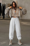 Full body front view of model posing in the loose-fit cropped sand french terry Deconstructed Crop Zip Hoodie with exposed seams and a JOAH BROWN logo patch on the sleeve