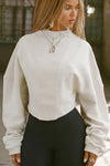 Front view of model posing in the off white french terry Dolman Pullover sweatshirt with oversized sleeves, a mock neckline, curved hem and ribbed panels at the front and back