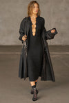 Full body front view of model posing in the fitted black flexrib Clasp Midi Dress with long sleeves, a crew neckline and front cutouts cinched together with metal clasp embellishments