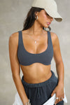 Front view of model posing in the stretchy and sculpting sueded navy contour bra with a deep scoop neckline and curved hem