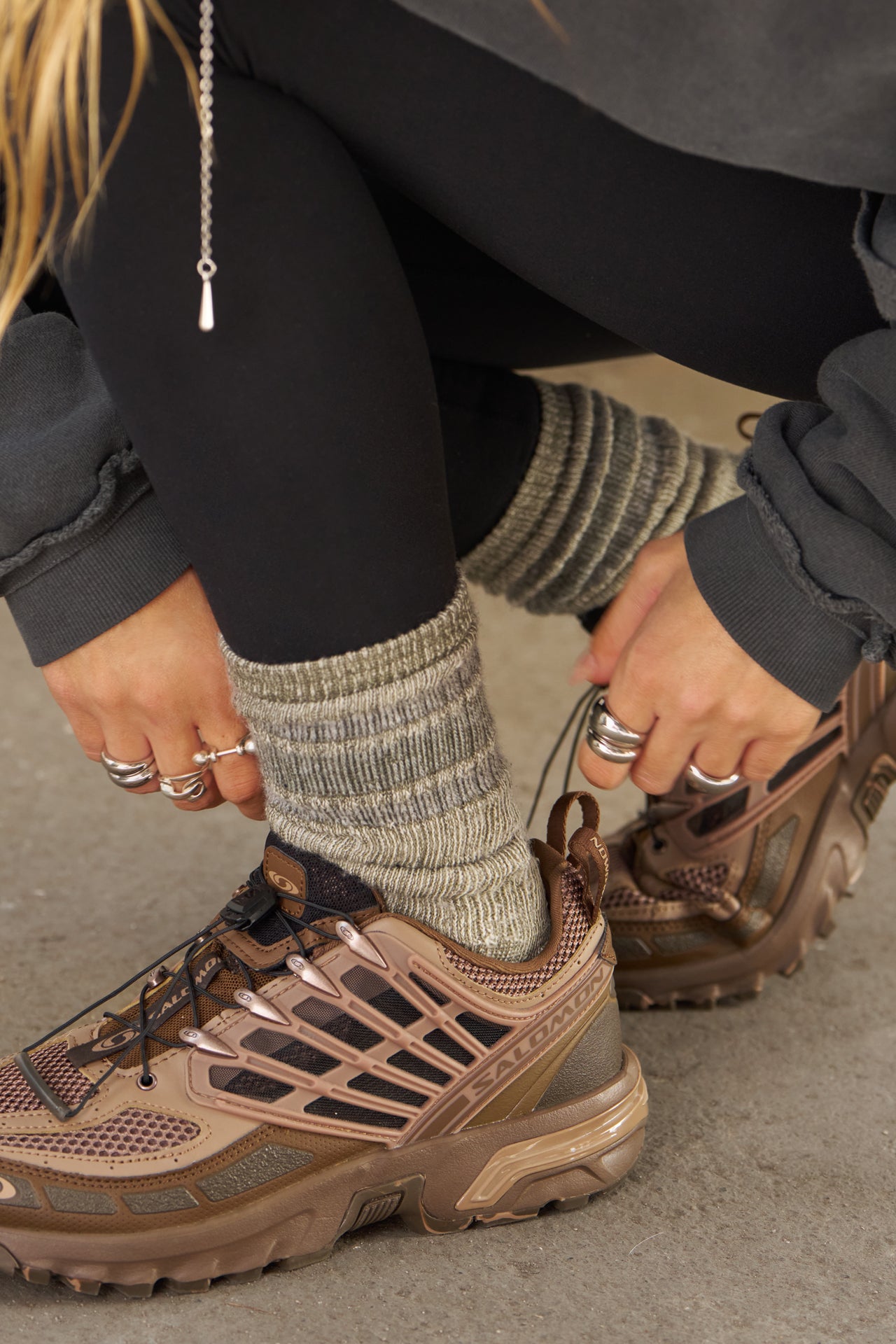 Close up side view of model adjusting the crew-style ribbed and soft heathered olive Merino Stripe Sock