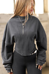 Front view of model posing in the charcoal french terry Dolman Pullover sweatshirt with oversized sleeves, a mock neckline, curved hem and ribbed panels at the front and back