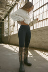 Full body side view of model posing in the off white french terry Dolman Pullover sweatshirt with oversized sleeves, a mock neckline, curved hem and ribbed panels at the front and back