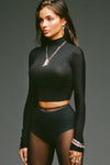 Front view of model posing in the fitted soft black modal Cropped Mock Neck Long Sleeve top with a raw cut hem