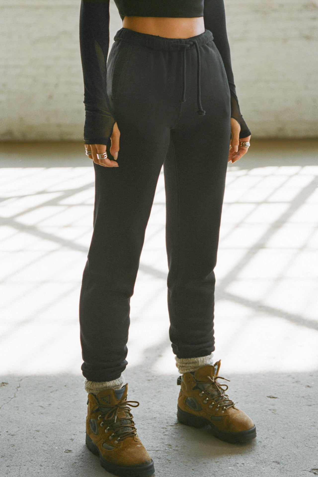 Front view of model from the waist down posing in the tapered black french terry Empire Jogger with side pockets and an elastic waistband and ankle cuffs