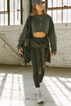 Full body front view of model posing in the cropped relaxed fit washed black cotton slouchy crop long sleeve top with a crew neckline, dropped shoulders and oversized sleeves