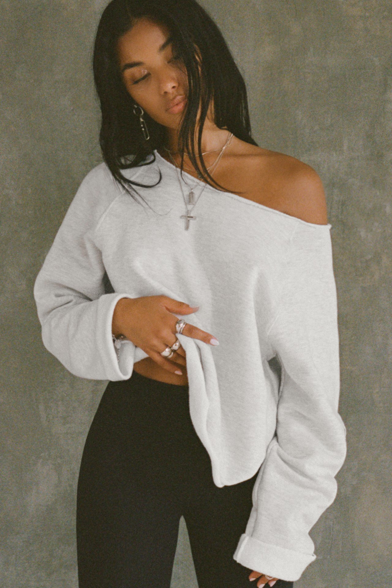 Front view of model posing in the oversized pearl grey french terry Slouchy Pullover Sweatshirt with a wide, off-the-shoulder neckline and a JOAH BROWN logo patch on the right sleeve