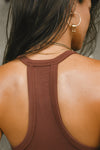 Close up detail back view of model posing in the fitted stretchy oxblood flexrib V Neck Racerback Tank with a narrow racerback silhouette and thin straps