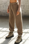 Side view of model from the waist down wearing the oversized loose fit cocoa french terry Oversized Jogger with an elastic waistband and ankle cuffs