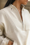 Close up detail front view of model posing in the oversized comfortable off white luxe french terry Retro Half Zip pullover sweatshirt with ribbed accents on the chest and sleeves, a hidden kangaroo pocket and a half zip collar