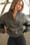 Front view of model posing in the oversized comfortable sage luxe french terry Retro Half Zip pullover sweatshirt with ribbed accents on the chest and sleeves, a hidden kangaroo pocket and a half zip collar