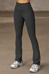 Front view of model from the waist down posing in the full length bootcut sueded onyx Second Skin Bootcut Legging with a wide v-shaped waistband and split detail at the leg opening