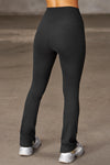 Back view of model from the waist down posing in the full length bootcut sueded onyx Second Skin Bootcut Legging with a wide v-shaped waistband and split detail at the leg opening