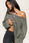 Front view of model posing in the oversized washed sage french terry Slouchy Pullover Sweatshirt with a wide, off-the-shoulder neckline and a JOAH BROWN logo patch on the right sleeve