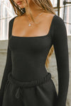 Front detail view of model posing in the fitted and stretchy black rib Square Neck Long Sleeve top with a wide square neckline