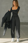 Full body front view of model posing in the fitted and stretchy black rib Square Neck Long Sleeve top with a wide square neckline