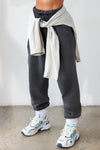 Front view of model from the waist down wearing the oversized loose fit washed black french terry Oversized Jogger with an elastic waistband and ankle cuffs